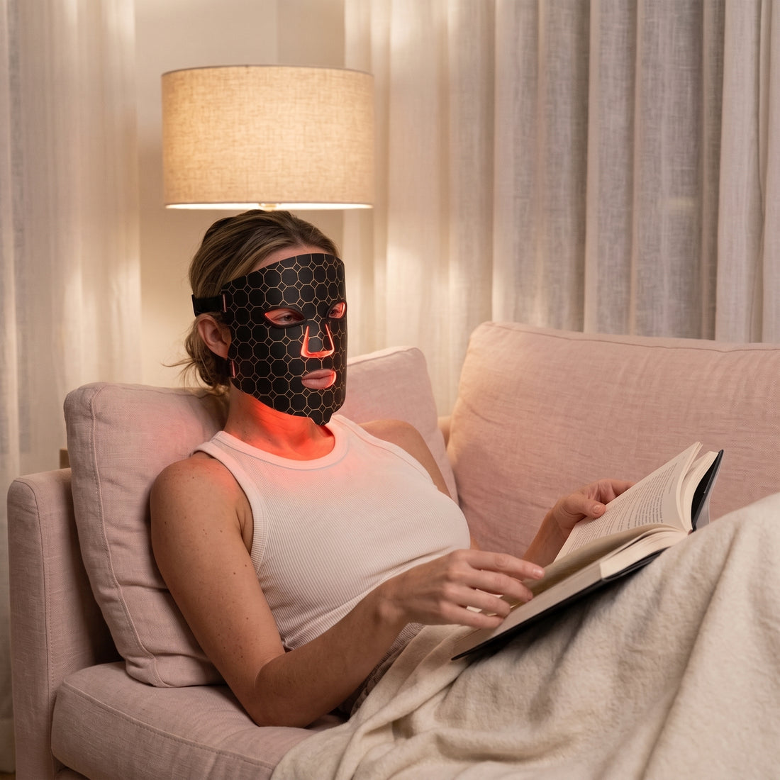 Evening | Woman wearing the Lumina Pro LED mask on a sofa in the evening, reading
