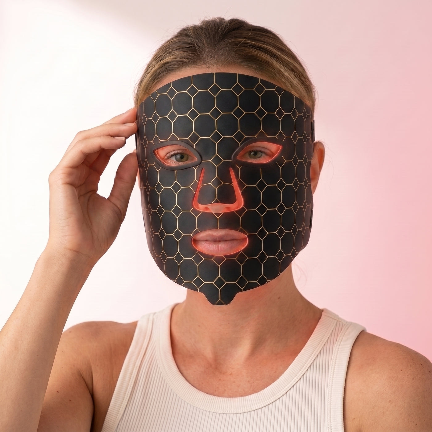 Woman wearing the Lumina Pro LED light therapy mask, hand at the temple