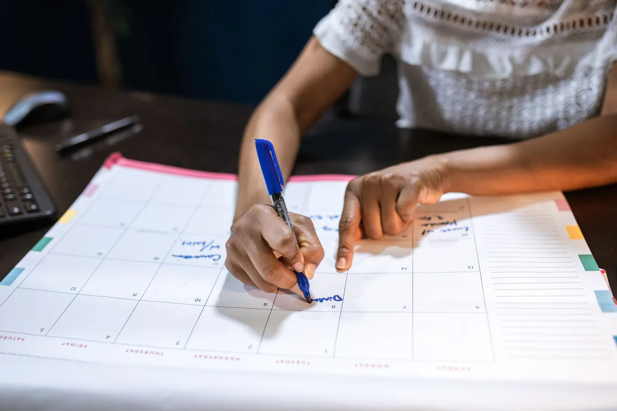 Woman marking appointments on a desk calendar