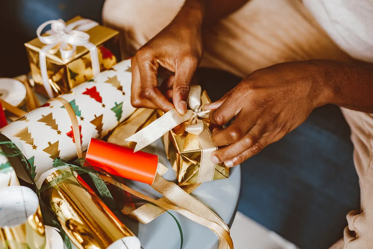 Hands tying ribbon on wrapped holiday gifts