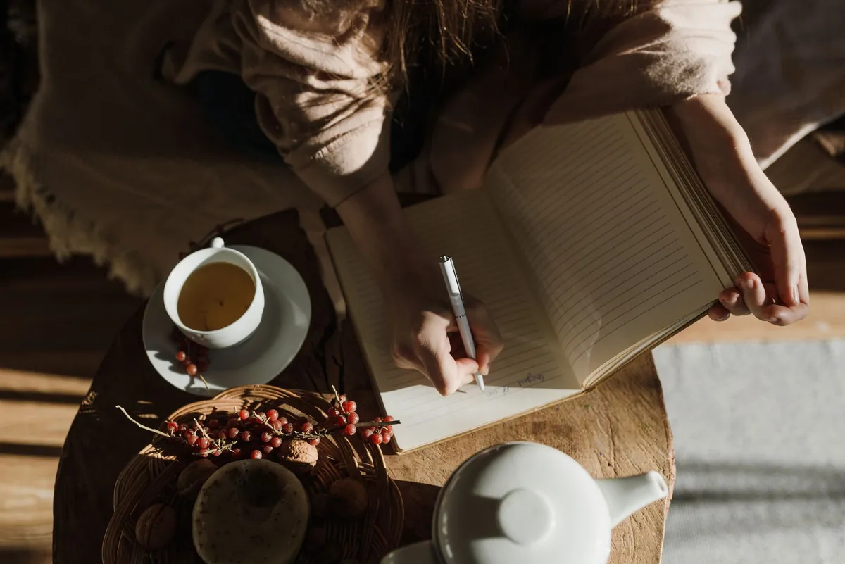 Person writing notes in a notebook in a cozy setting