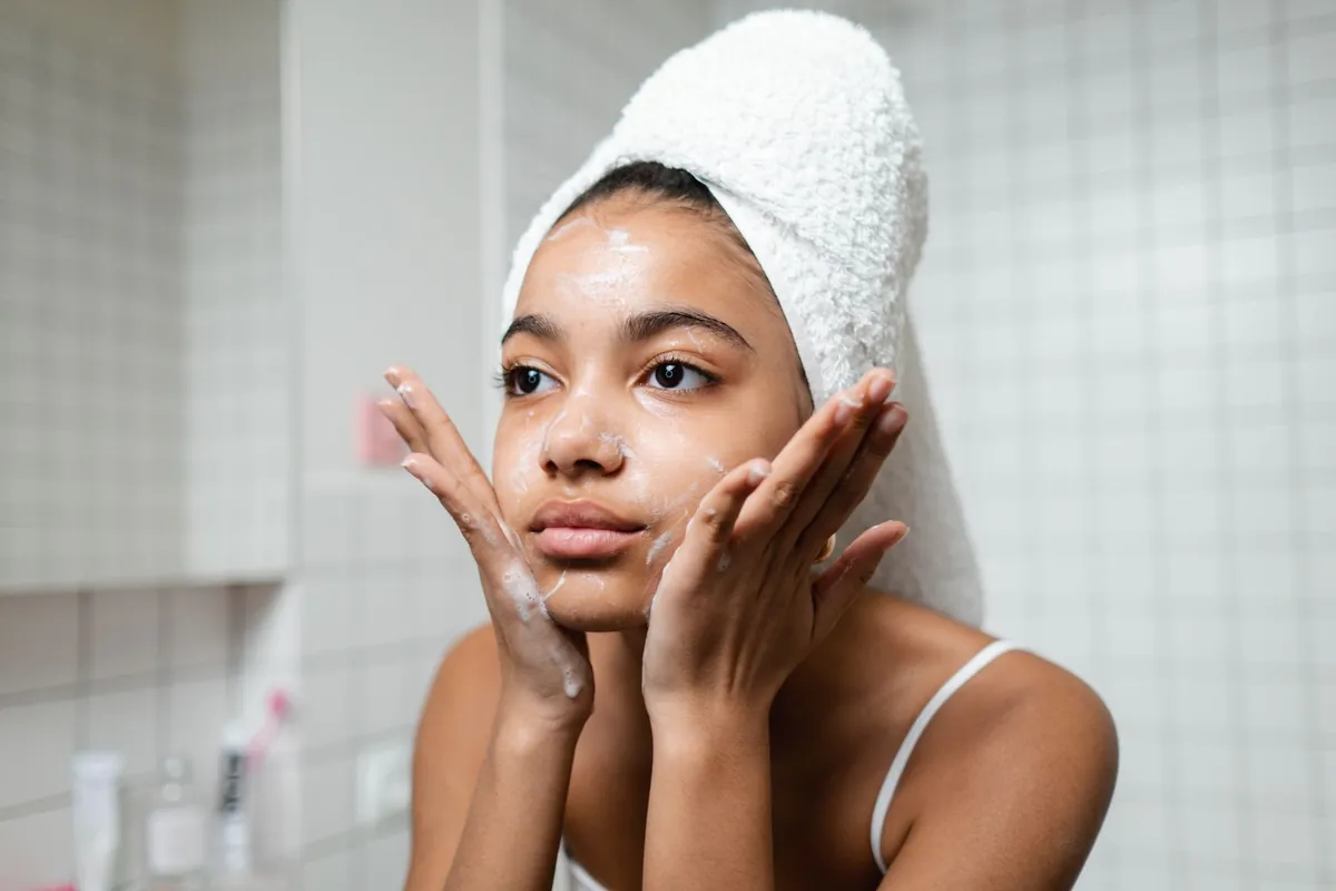 Woman washing her face with her hair wrapped in a towel