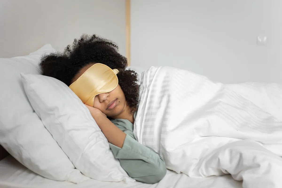 Woman resting in bed with her eyes covered