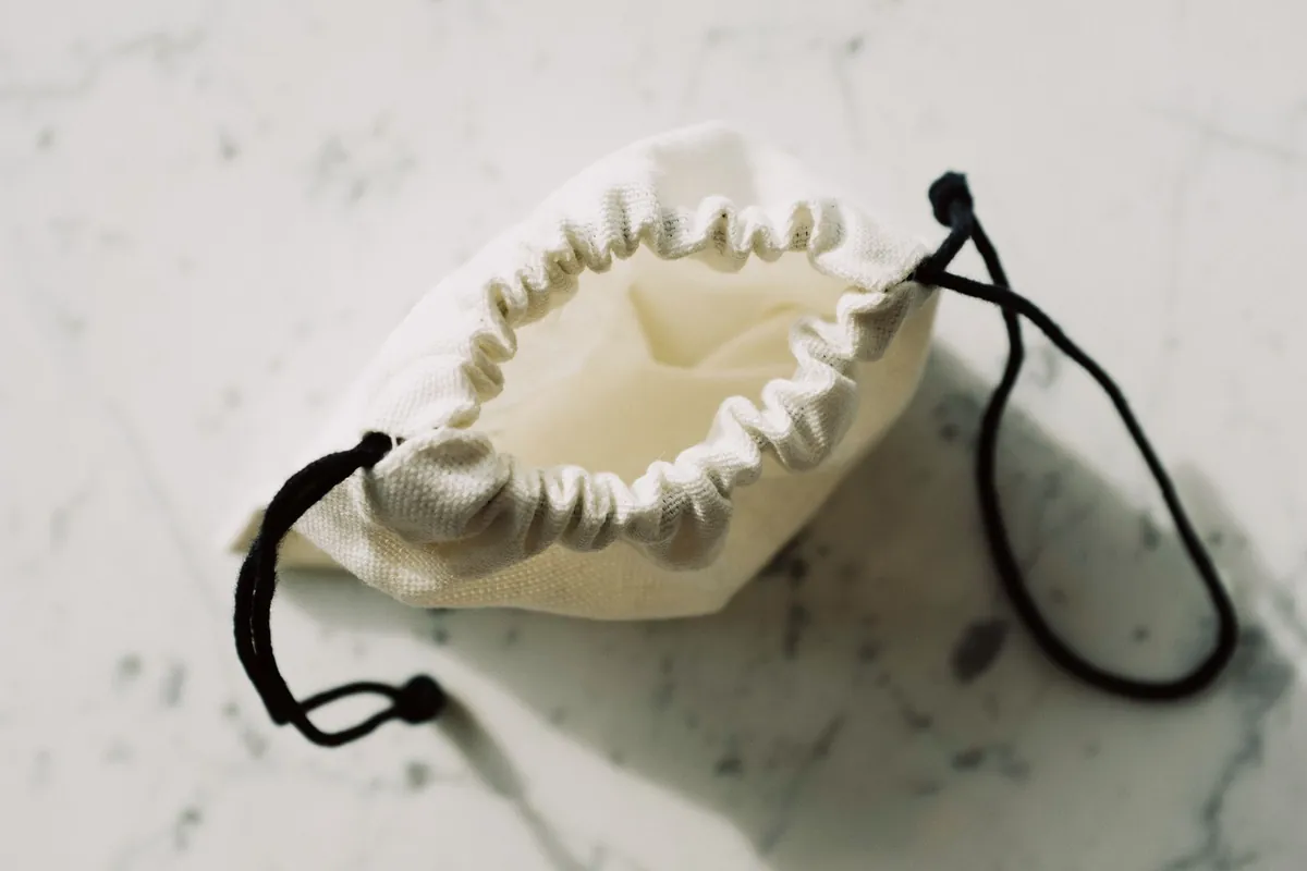 White drawstring fabric pouch on a marble surface