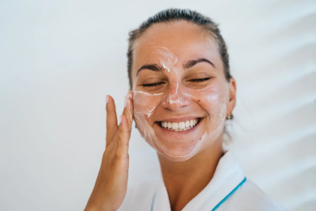 Smiling woman applying face cream