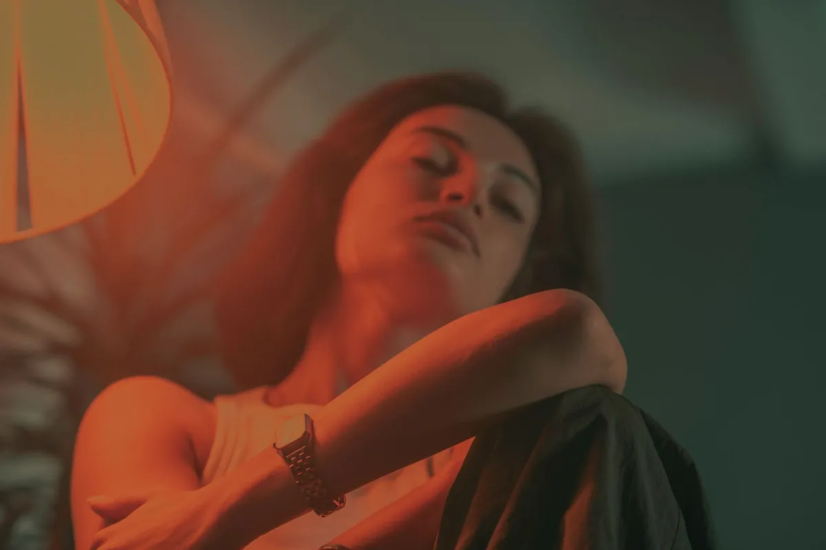 Woman with her eyes closed, relaxing in warm lamp light
