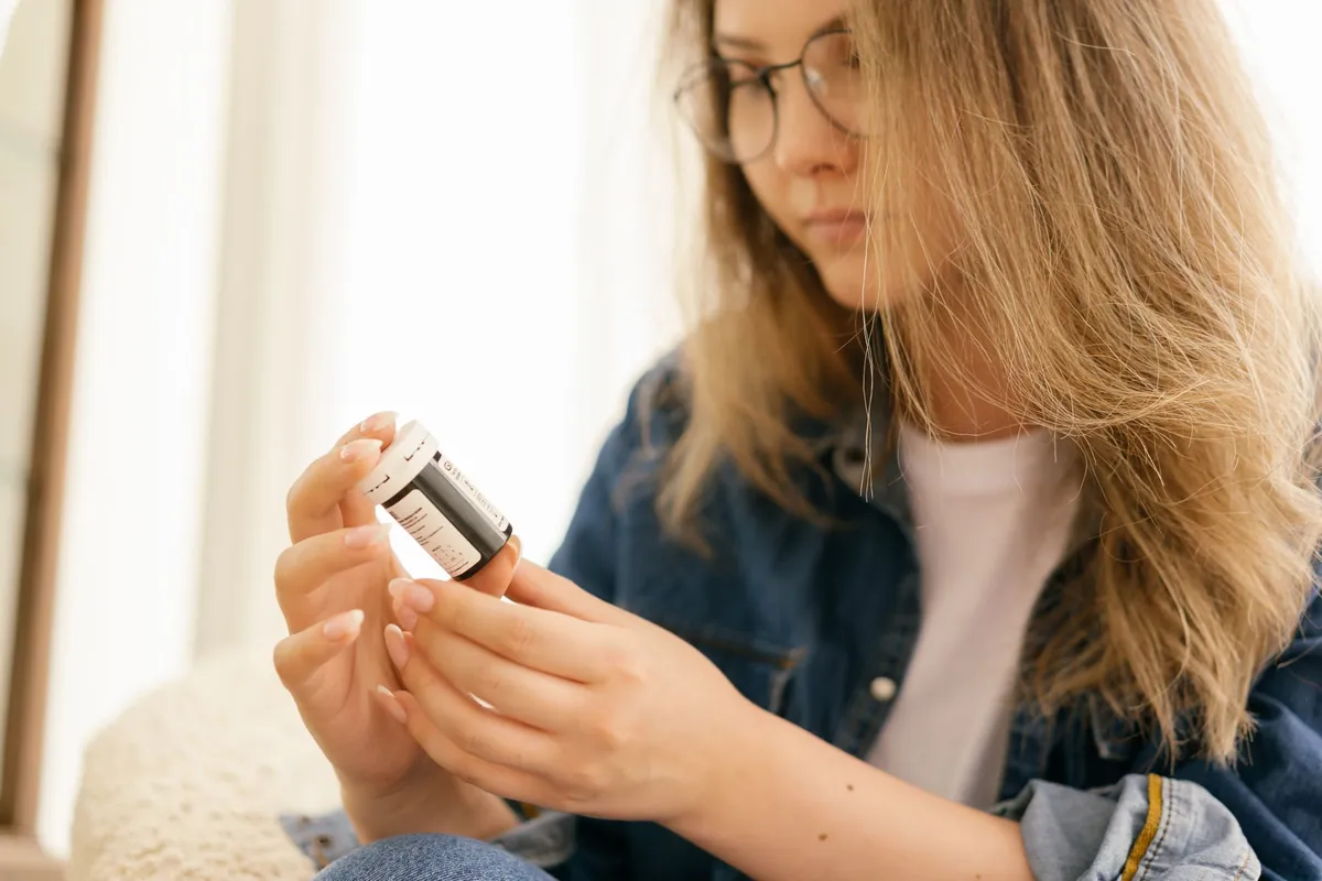 Woman checking the label on a medication bottle